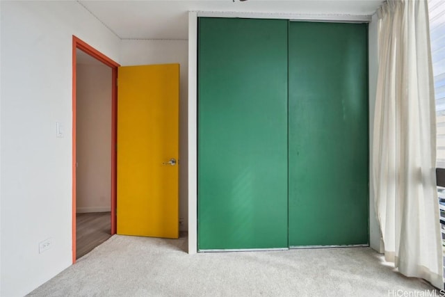 unfurnished bedroom featuring light carpet and a closet