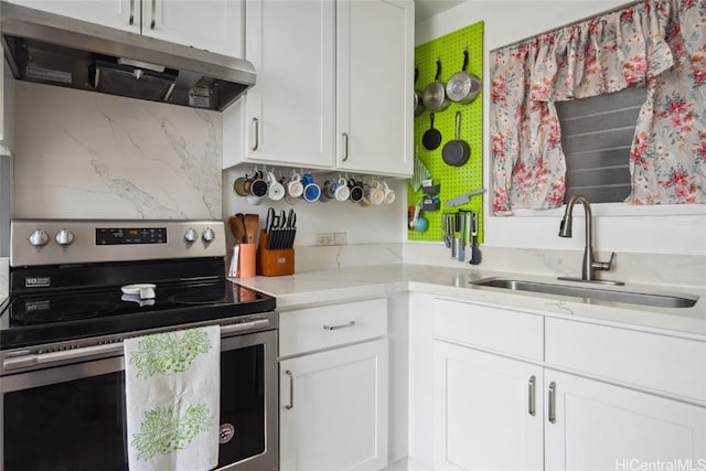 kitchen with white cabinets, decorative backsplash, stainless steel electric range oven, and sink