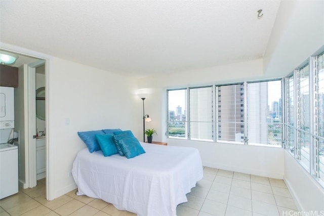 bedroom featuring light tile patterned floors, a textured ceiling, and stacked washer and dryer