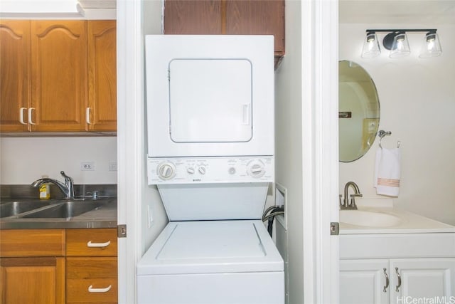 laundry area with stacked washer / drying machine and sink