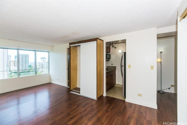 unfurnished room with dark hardwood / wood-style flooring and a textured ceiling