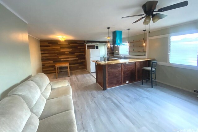 kitchen with freestanding refrigerator, open floor plan, wood walls, wood finished floors, and a peninsula