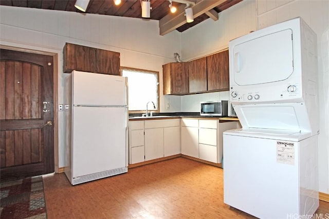 kitchen featuring wooden ceiling, white refrigerator, sink, vaulted ceiling with beams, and stacked washer / drying machine