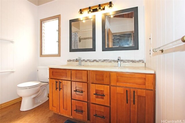 full bathroom with double vanity, wood finished floors, a sink, and toilet