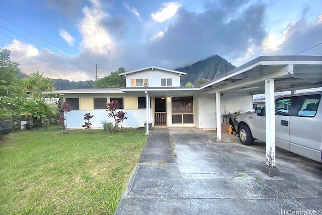 view of front facade with a carport, a front yard, a mountain view, and driveway