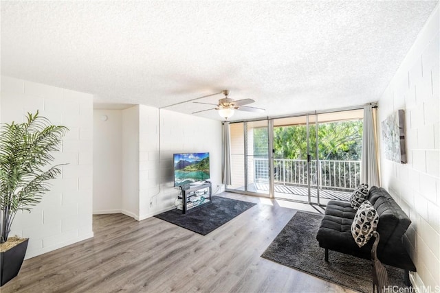 living room with ceiling fan, expansive windows, a textured ceiling, and hardwood / wood-style floors