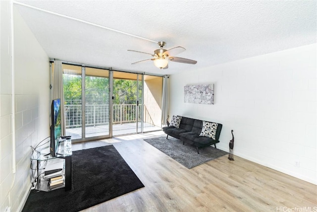 living room featuring a textured ceiling, ceiling fan, light wood-type flooring, and expansive windows