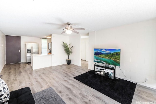 living room with light wood-type flooring, ceiling fan, and a textured ceiling