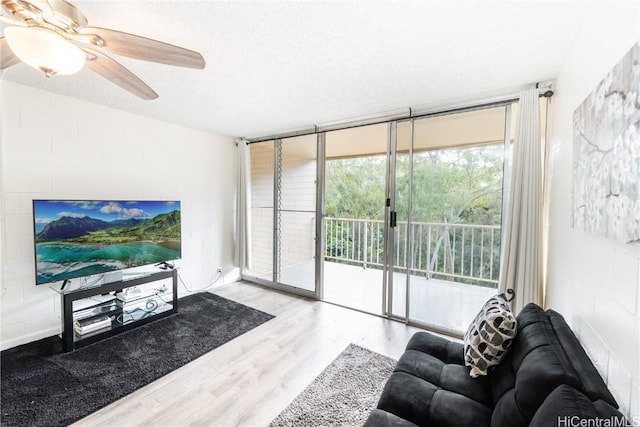 living room featuring a textured ceiling, a wealth of natural light, a wall of windows, and light hardwood / wood-style floors