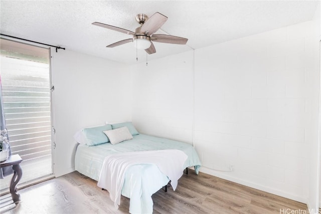 bedroom with ceiling fan, a textured ceiling, and hardwood / wood-style flooring