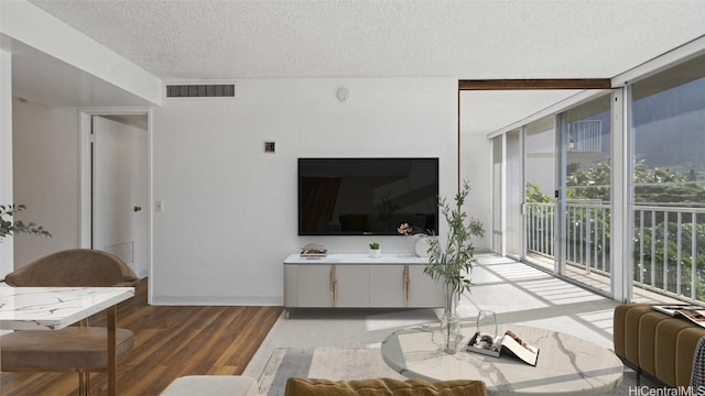 living room featuring a textured ceiling, hardwood / wood-style flooring, and floor to ceiling windows