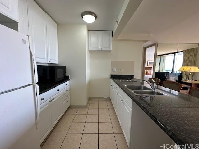 kitchen with white refrigerator, white cabinets, sink, and light tile patterned floors