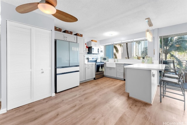 kitchen featuring a breakfast bar, kitchen peninsula, a wealth of natural light, hanging light fixtures, and appliances with stainless steel finishes