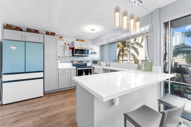 kitchen featuring a kitchen breakfast bar, a wealth of natural light, stainless steel appliances, and tasteful backsplash