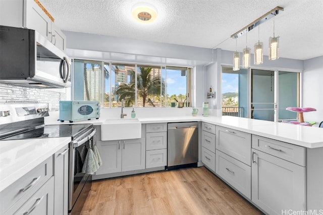 kitchen featuring sink, gray cabinetry, stainless steel appliances, and light wood-type flooring