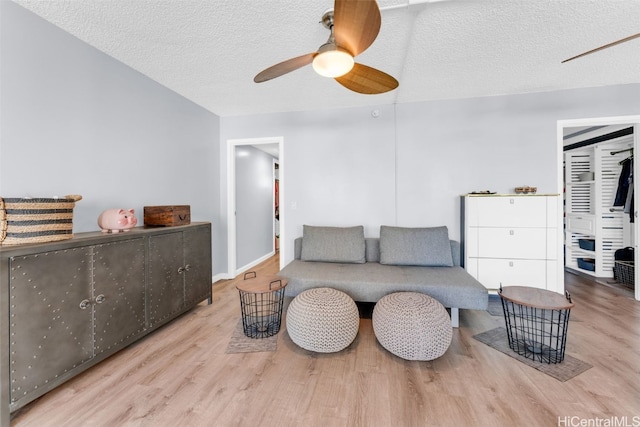 living room featuring ceiling fan, a textured ceiling, and light hardwood / wood-style flooring