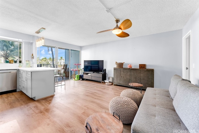 living room featuring ceiling fan, a textured ceiling, and light wood-type flooring