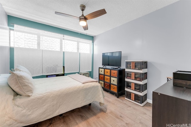 bedroom featuring ceiling fan, a textured ceiling, and light hardwood / wood-style flooring