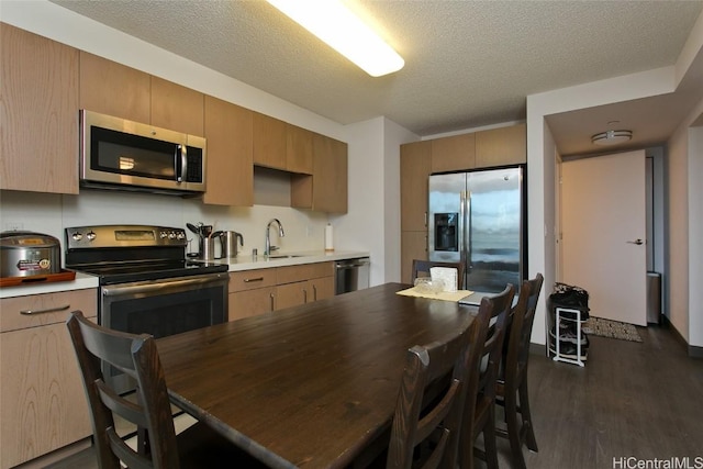 kitchen with dark wood-type flooring, a textured ceiling, appliances with stainless steel finishes, and sink