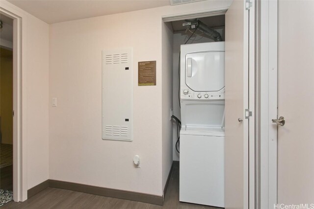 clothes washing area featuring stacked washer and dryer and dark wood-type flooring