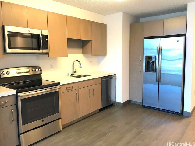 kitchen with light brown cabinetry, sink, a textured ceiling, appliances with stainless steel finishes, and dark hardwood / wood-style flooring