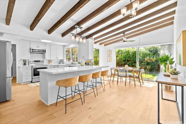 kitchen featuring light countertops, a peninsula, a kitchen bar, stainless steel appliances, and light wood-type flooring
