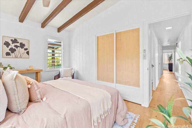 bedroom featuring lofted ceiling with beams, multiple windows, a ceiling fan, and light wood-type flooring