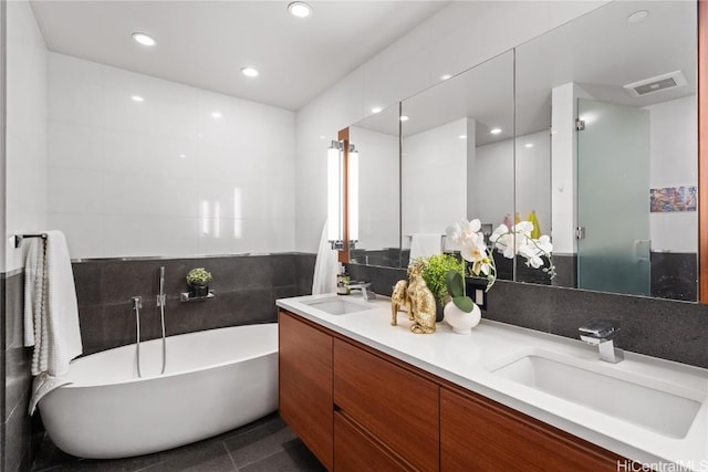 bathroom featuring tile walls, tile patterned flooring, a tub to relax in, and vanity