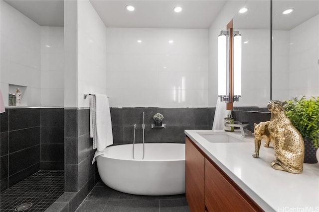 bathroom featuring tile walls, a bath, vanity, and tile patterned floors