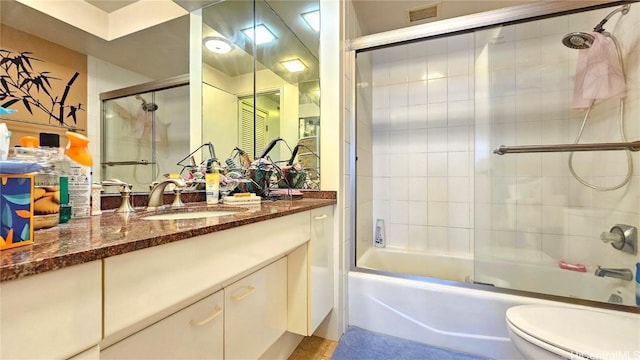 full bathroom featuring combined bath / shower with glass door, toilet, and vanity