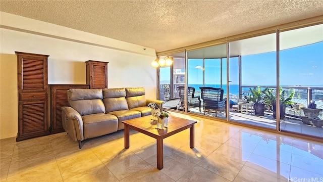 living room featuring a textured ceiling, a water view, and a wall of windows