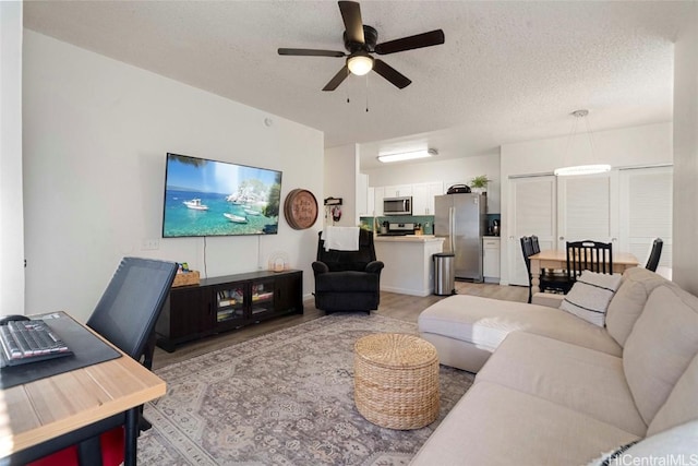 living room with ceiling fan, light hardwood / wood-style floors, and a textured ceiling