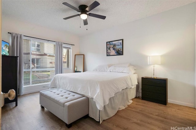 bedroom featuring hardwood / wood-style flooring, a textured ceiling, and ceiling fan