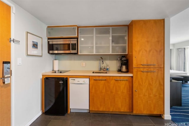 kitchen featuring white dishwasher, dark tile patterned flooring, a sink, light countertops, and stainless steel microwave