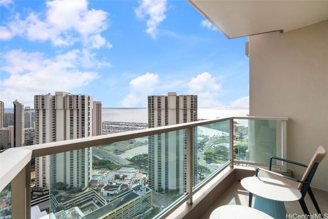 balcony featuring a water view and a city view