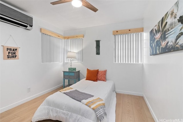 bedroom featuring hardwood / wood-style floors, an AC wall unit, and ceiling fan