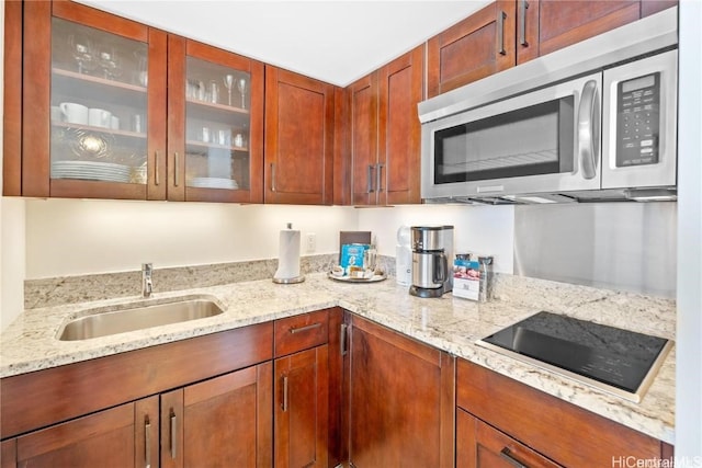 kitchen with sink, black electric cooktop, and light stone countertops