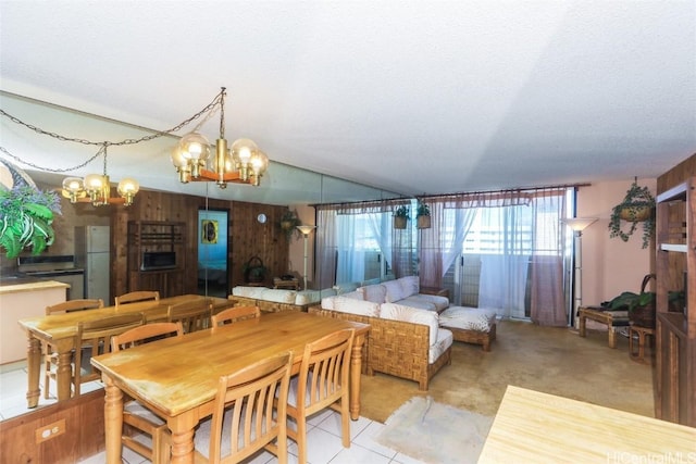 dining room with an inviting chandelier, wooden walls, and a textured ceiling