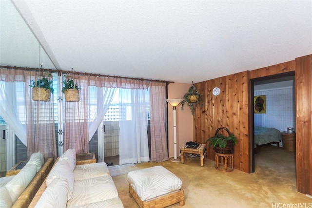 living room featuring carpet floors, a textured ceiling, and wood walls