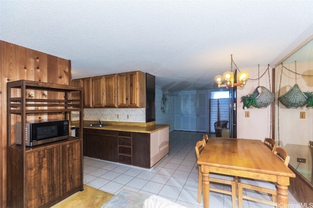 kitchen with an inviting chandelier, light tile patterned flooring, a textured ceiling, and sink