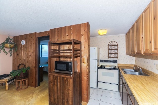 kitchen featuring white appliances, a textured ceiling, light tile patterned flooring, and sink