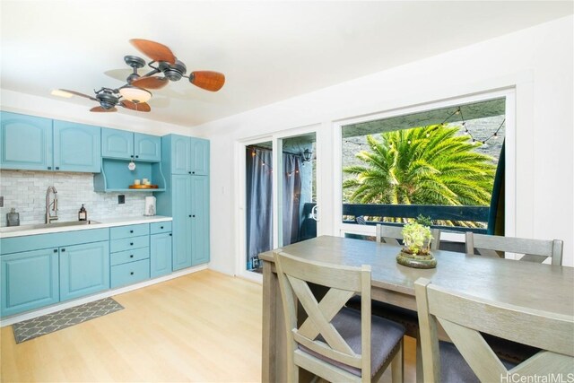 kitchen featuring light hardwood / wood-style floors, sink, backsplash, ceiling fan, and blue cabinets