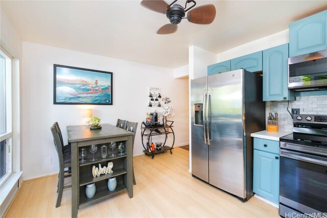 kitchen with light hardwood / wood-style floors, blue cabinetry, backsplash, and appliances with stainless steel finishes