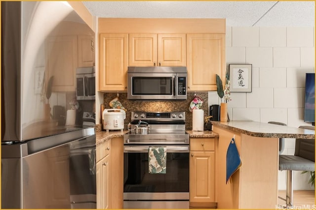 kitchen featuring backsplash, kitchen peninsula, light brown cabinetry, and stainless steel appliances