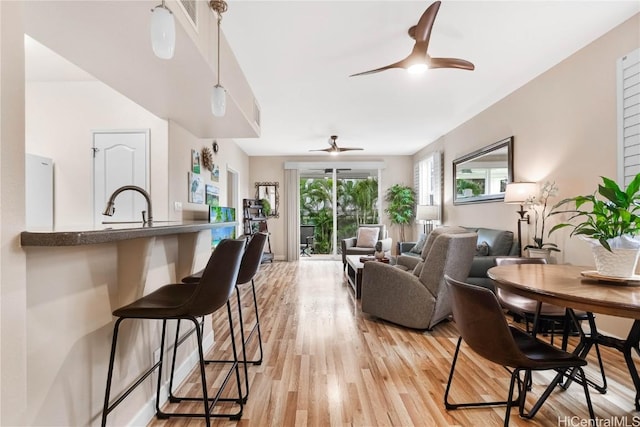 living room with ceiling fan, sink, and light wood-type flooring