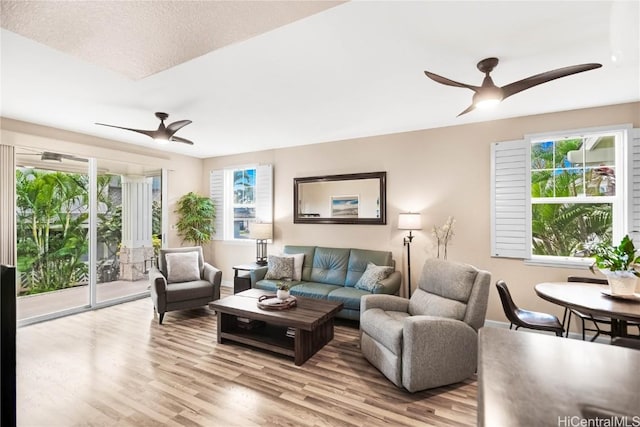 living room featuring ceiling fan, a healthy amount of sunlight, and light wood-type flooring