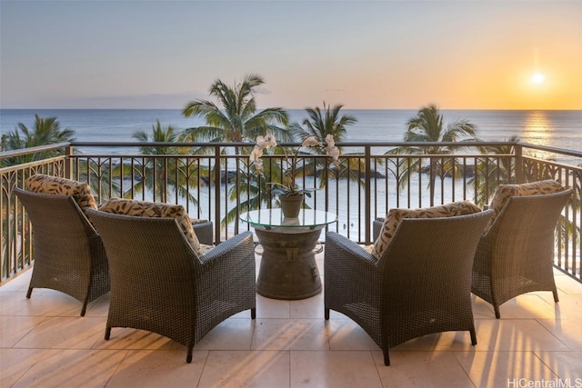 balcony at dusk featuring a water view