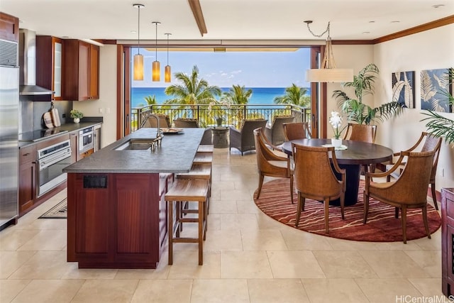 kitchen with black electric stovetop, a water view, stainless steel oven, sink, and decorative light fixtures