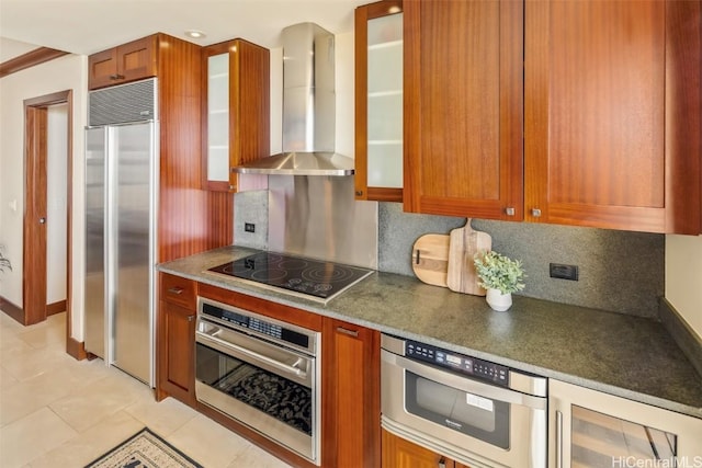 kitchen with appliances with stainless steel finishes, backsplash, wall chimney exhaust hood, and light tile patterned floors