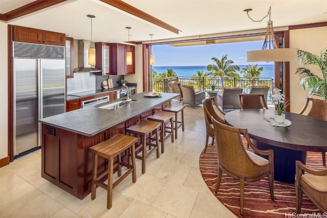 kitchen with stainless steel built in refrigerator, sink, decorative light fixtures, a water view, and wall chimney exhaust hood